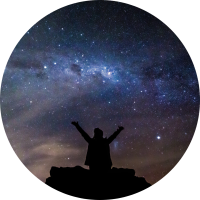 picture of a person sitting on top of a mountain with their arms reaching up to the night sky